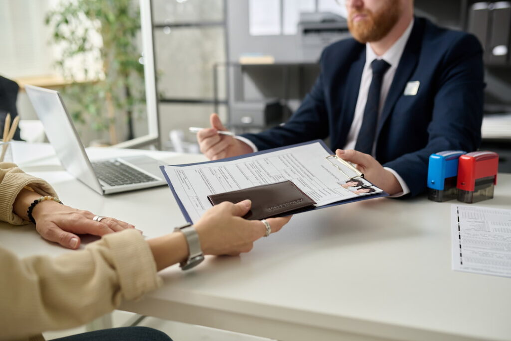 a person hands their lawyer a clipboard with their identification