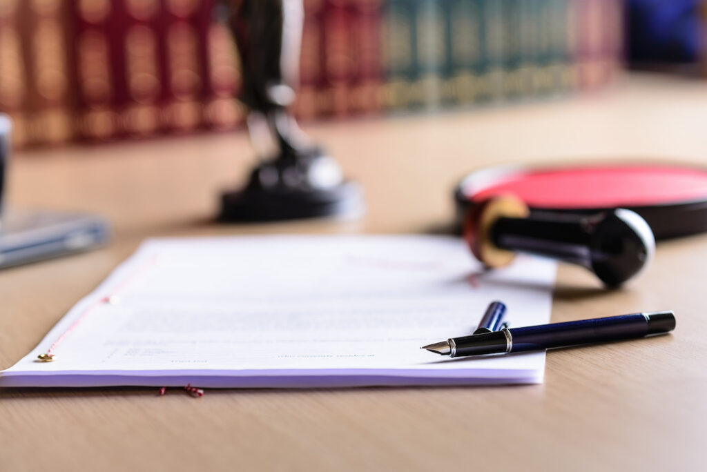 a lawyers desk with a pen and paper ready to be signed