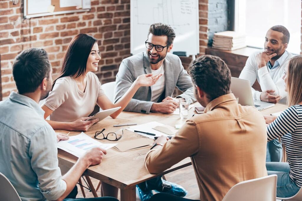 a team of people smile together while discussing business plans around an office table