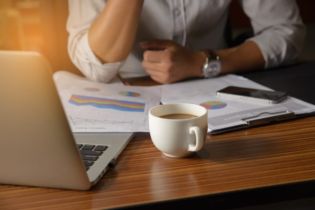 an office employee sits in front of a laptop with company graphics printed out around it