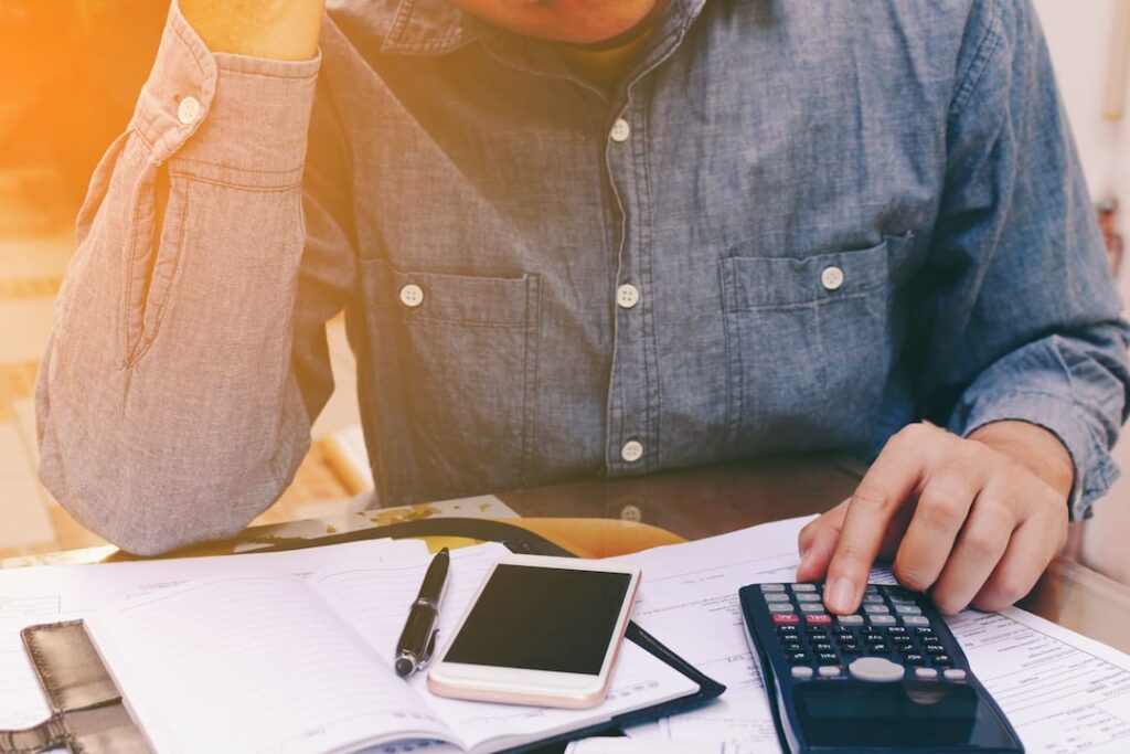 a person typing on a calculator with business documents set out around them on a table