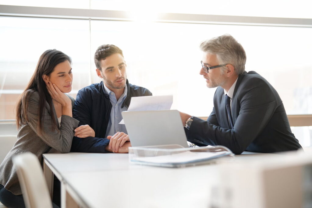 lawyer sits at his desk and explains document to business couple