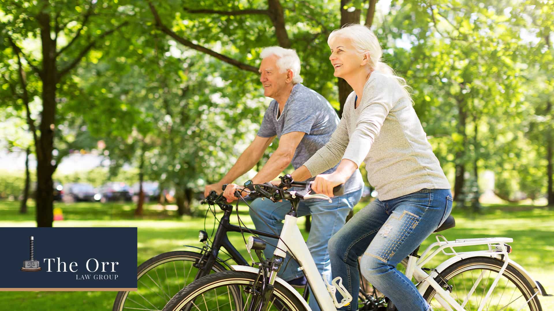 An elderly man and woman riding their bikes in a park.